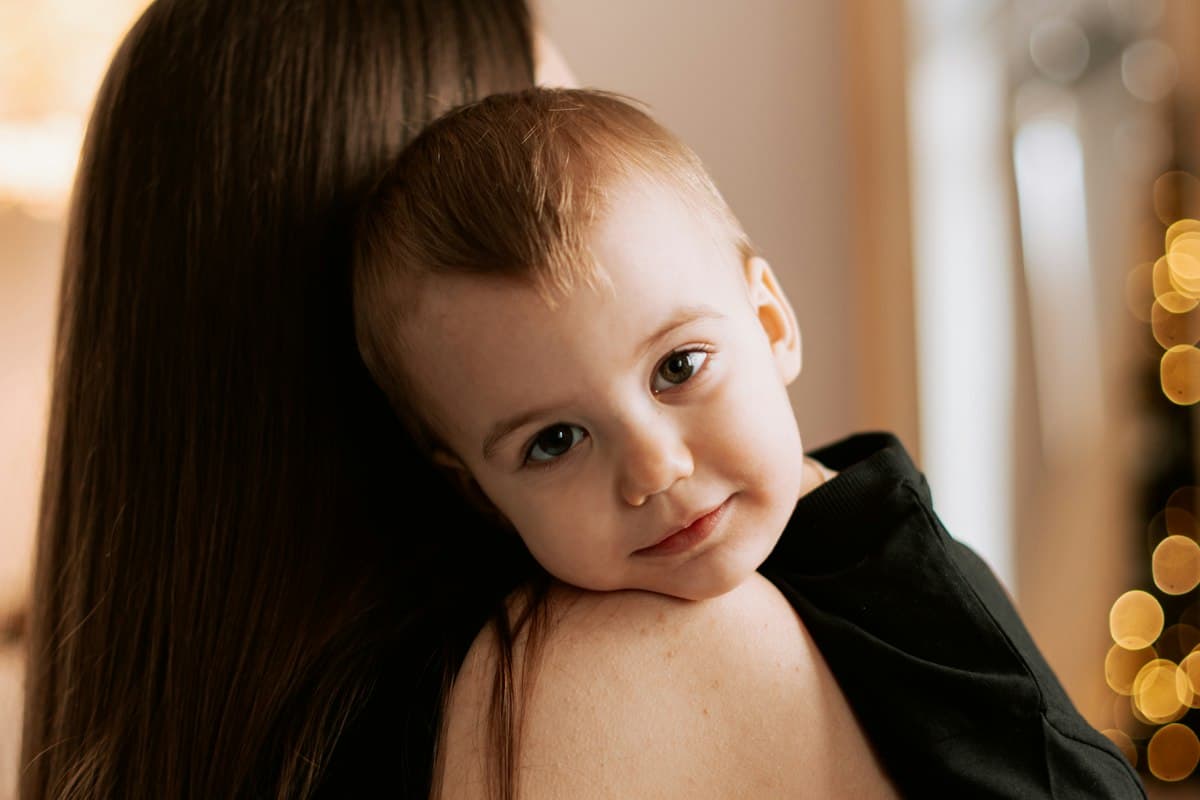 Tout-petit blotti sur l'épaule de sa mère, angoisse de séparation chez l'enfant