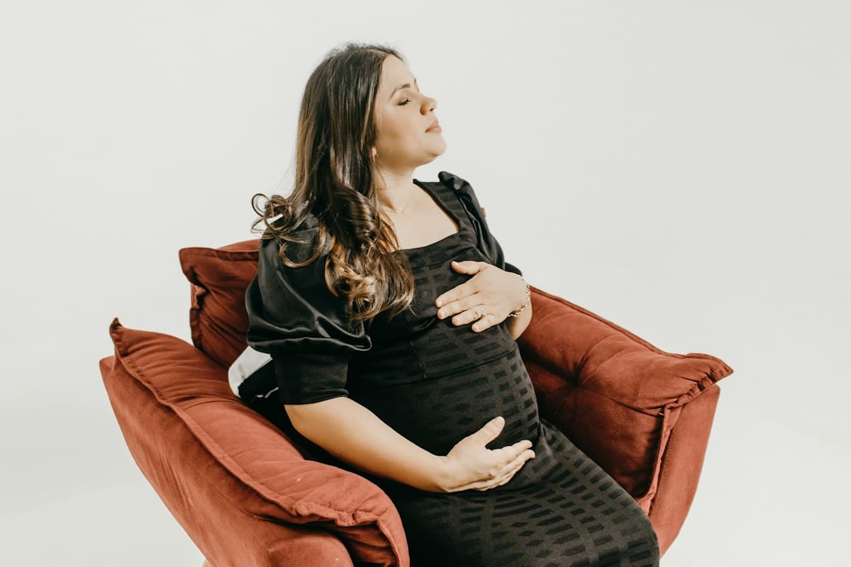 Femme enceinte apaisée dans un fauteuil, soulagée de sa douleur ligamentaire de grossesse