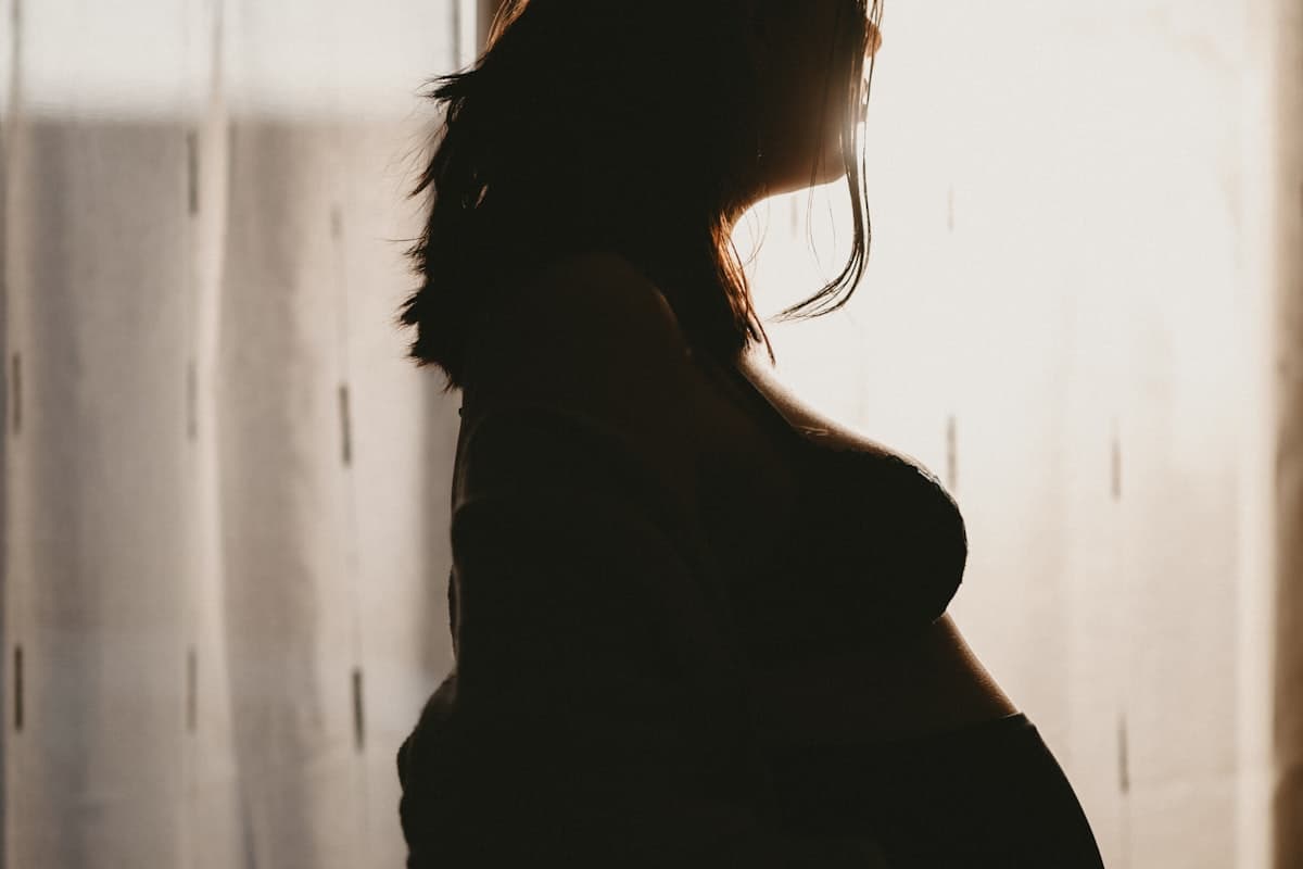 Femme enceinte sereine à contre-jour avant de connaître le sexe du bébé