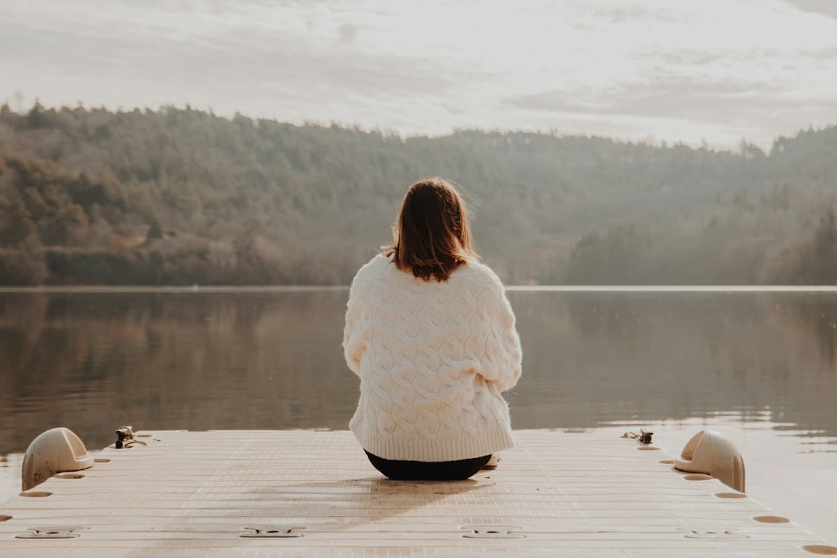 Femme assise sur un ponton face au lac, soigner l'anxiété durablement