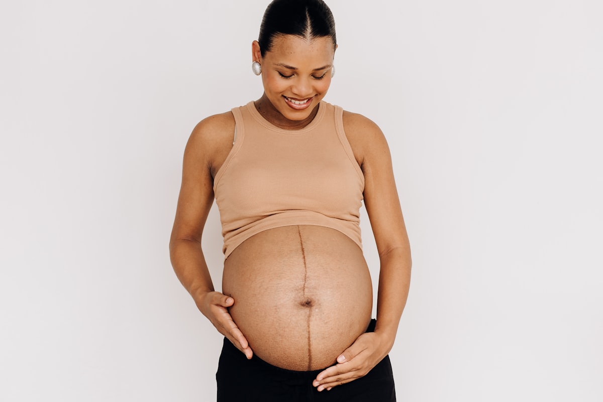Femme enceinte souriante, main sur le ventre, sereine face a l'anxiete