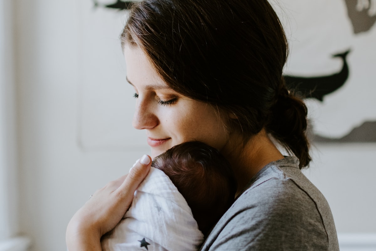 Maman tenant tendrement son bébé endormi, ostéopathie et sommeil de bébé