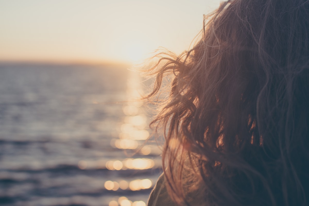 Femme sereine face à la mer au coucher du soleil, prendre le temps pour le dépistage du col de l'utérus