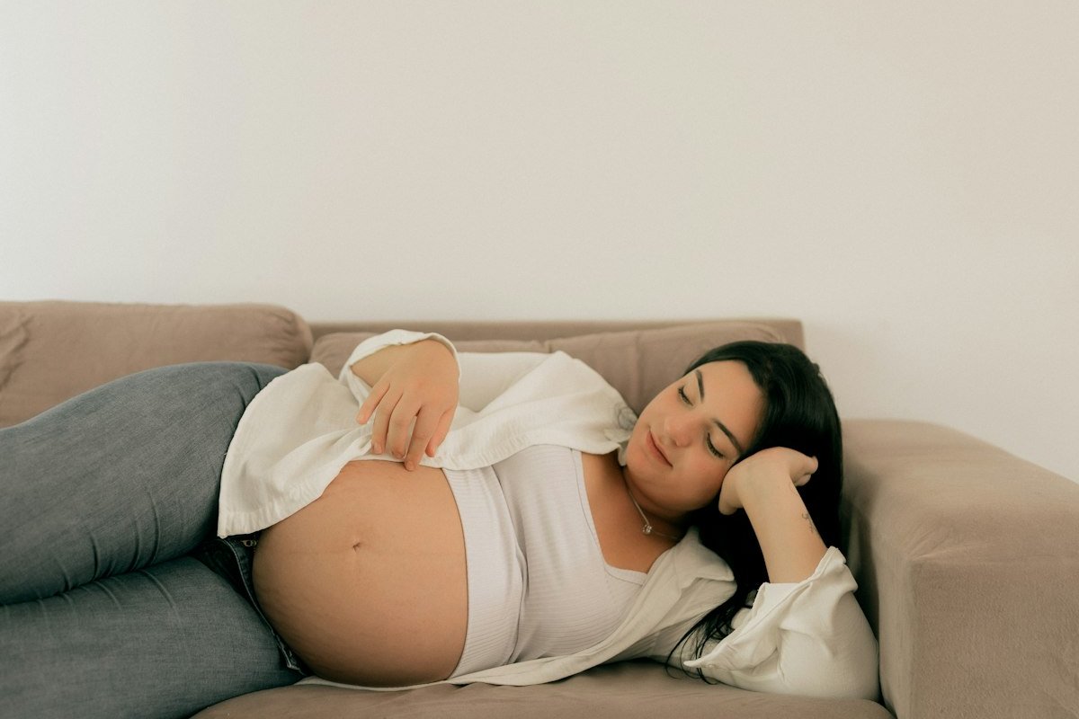 Femme enceinte se reposant sur un canapé, soulager la douleur au pubis pendant la grossesse