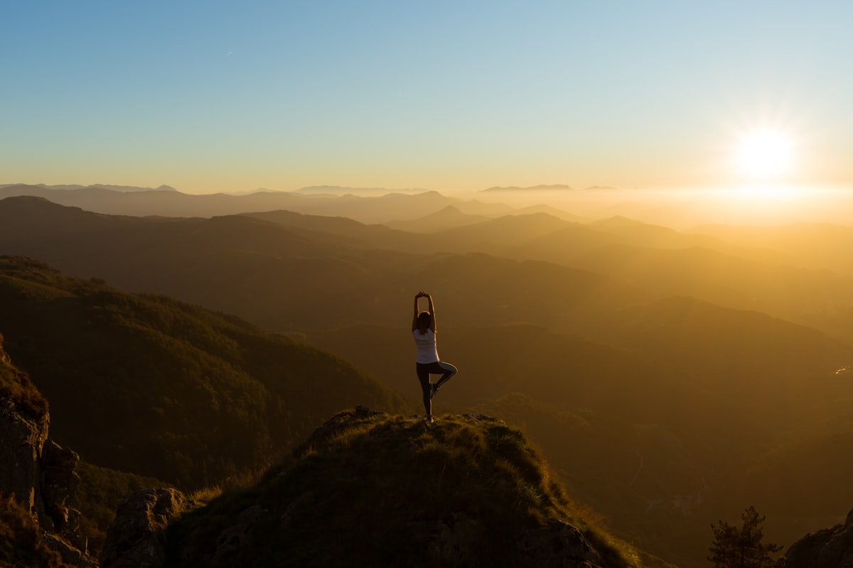 Femme pratiquant le yoga au coucher du soleil pour apaiser son hypersensibilité