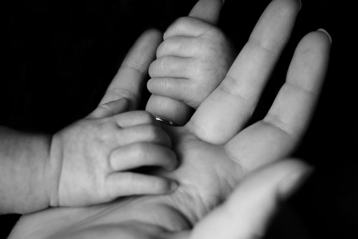 Bébé agrippant le doigt d'un parent, éveil et kiné du nourrisson