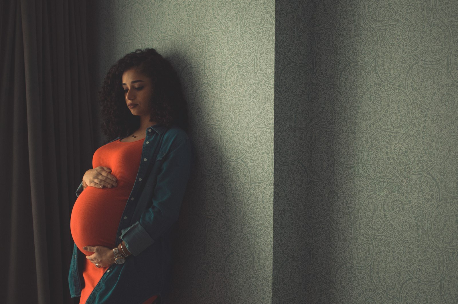 Femme enceinte apaisée à la maison, une main posée sur son ventre
