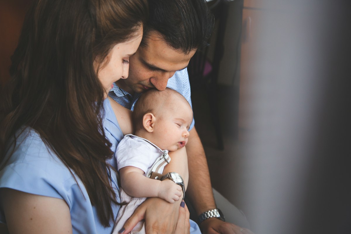 Couple de jeunes parents serrant tendrement leur bébé, se faire aider après la naissance