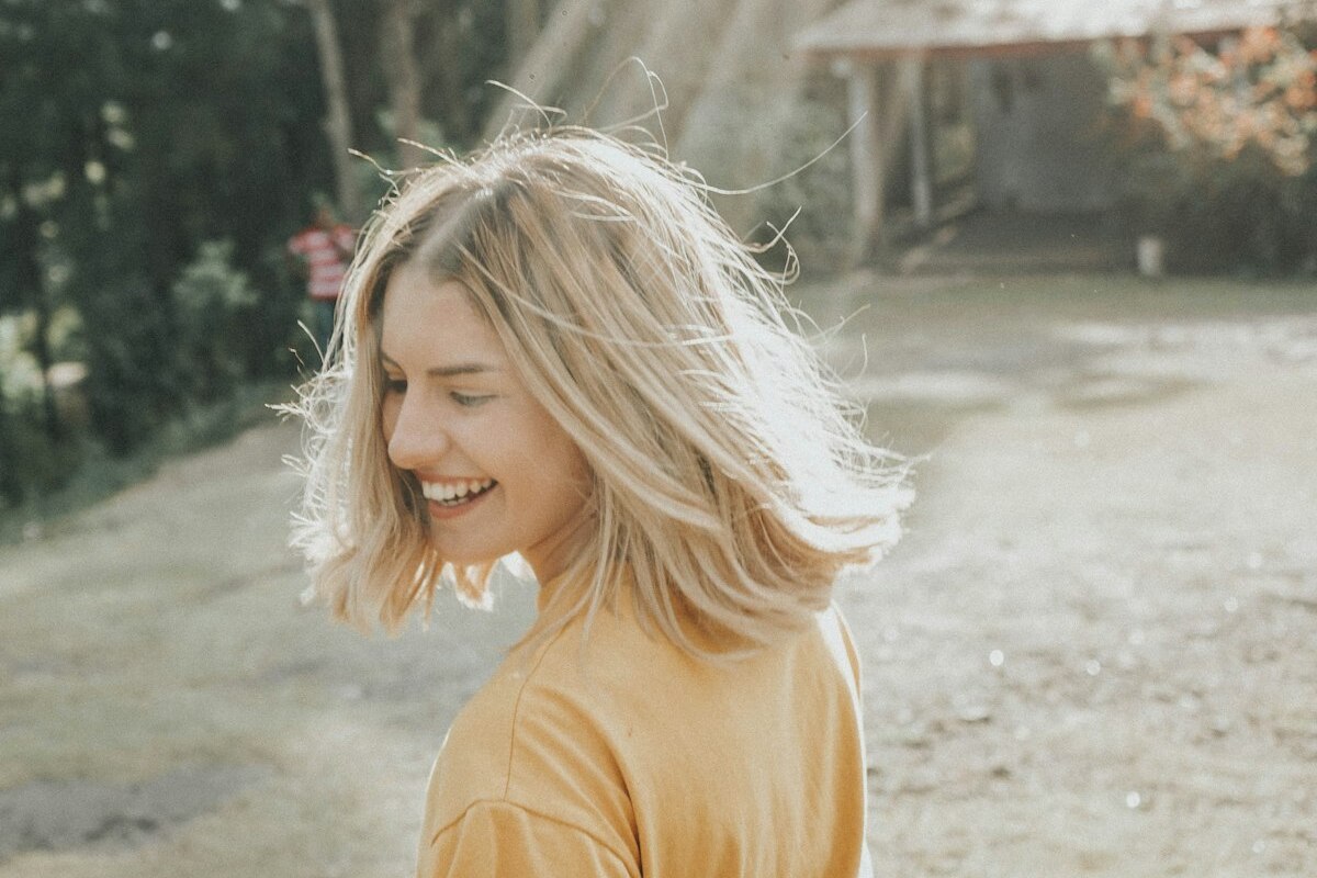 Femme épanouie souriant en pleine lumière après avoir surmonté l'anxiété sociale