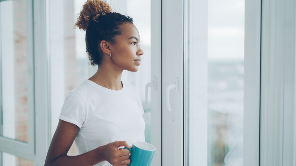 Jeune femme apaisée près d une fenetre, accompagnement par un psychologue TCC