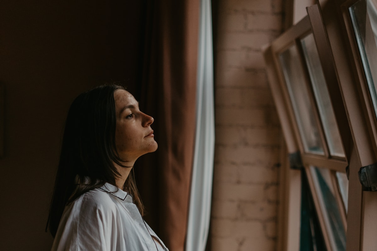 Future maman pensive près d'une fenêtre, dans l'attente de connaître le sexe du bébé