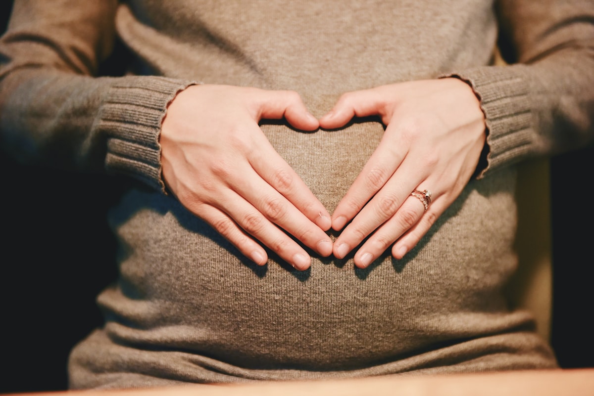 Mains formant un cœur sur le ventre d'une femme enceinte