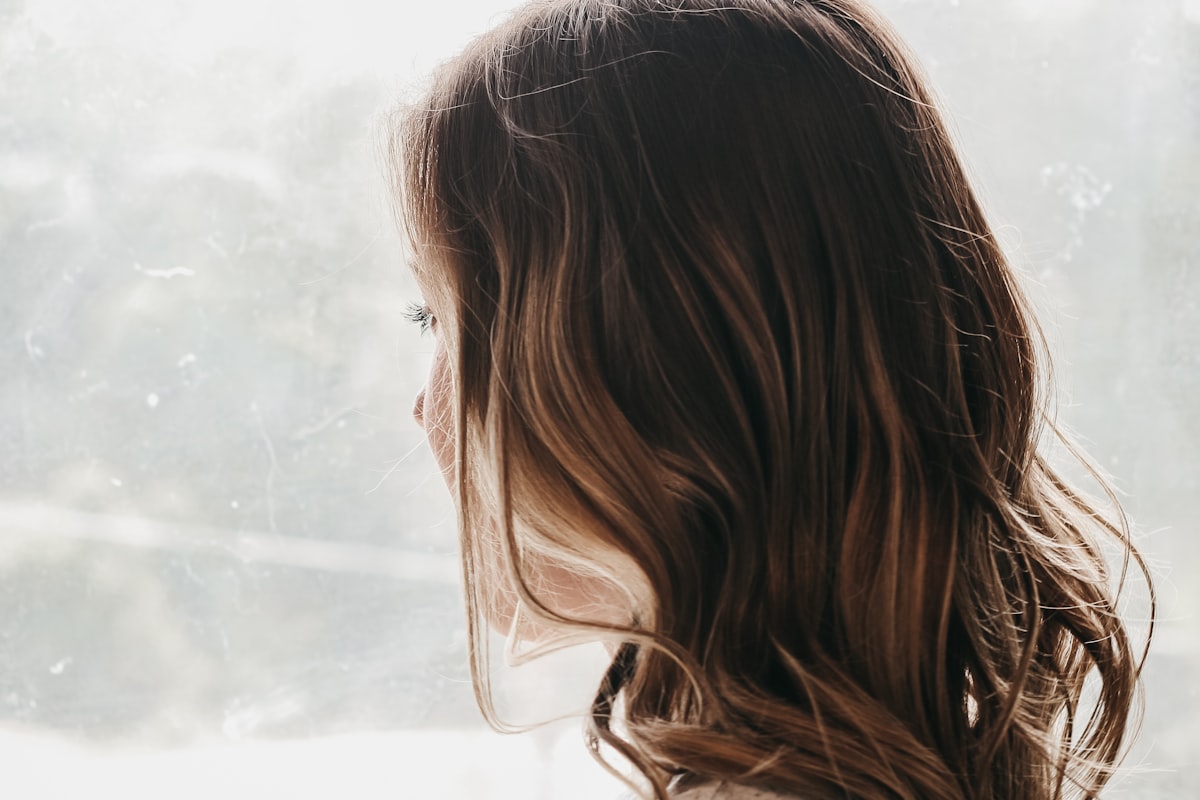 Femme pensive regardant par la fenêtre, traverser le syndrome du nid vide